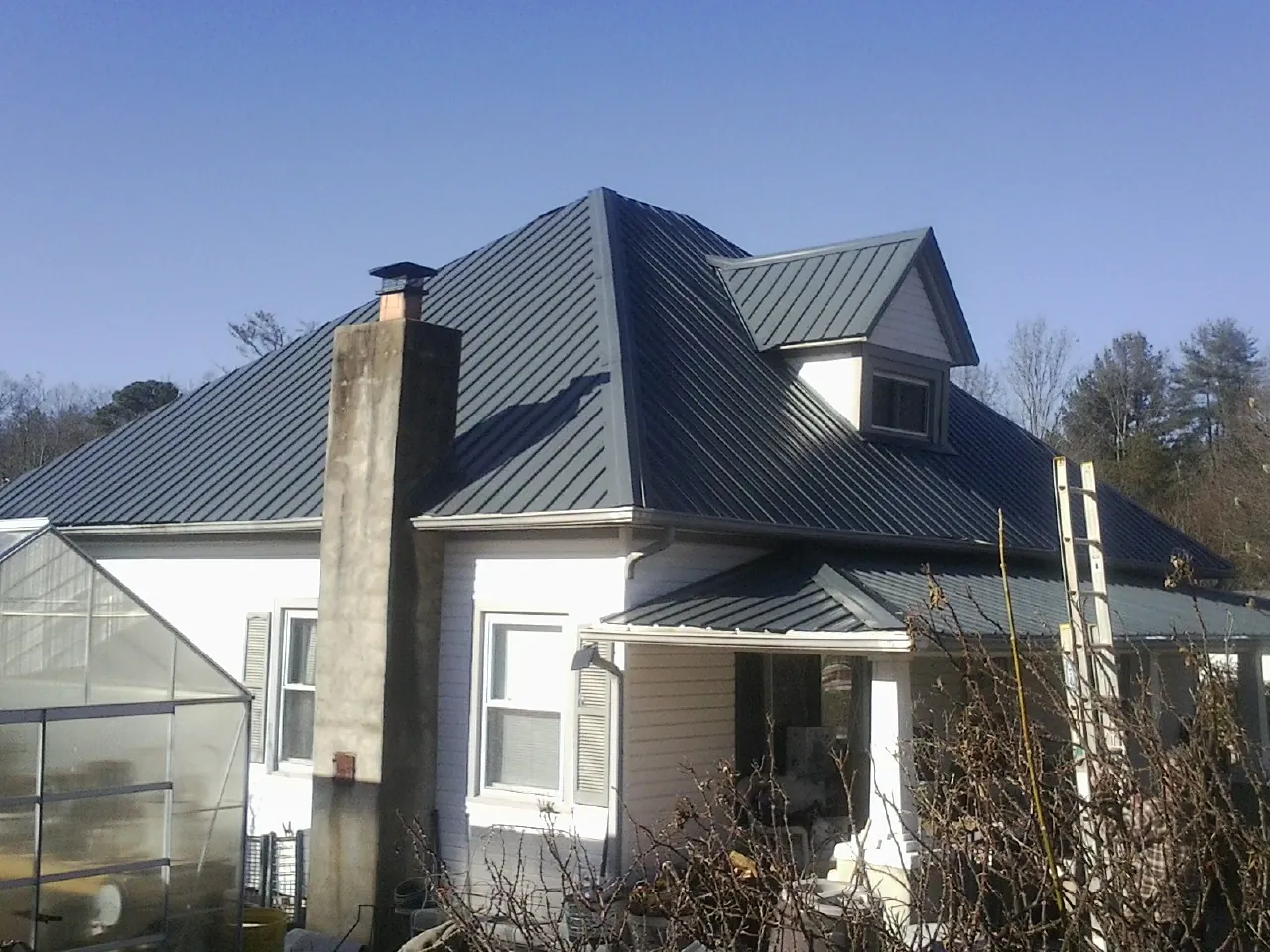 Dark blue standing seam metal roof on a white farmhouse with dormer — Slate & Tile Roof Repair by Roofing Brothers in Ellijay