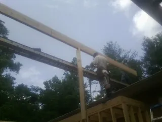 Carpenter setting a ridge beam over a new addition frame — Ice Dam Removal by Roofing Brothers in Ellijay