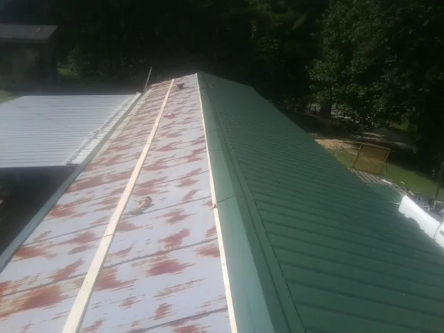 Old rusted panels beside newly installed green metal roofing — Wind Damage Roof Repair by Roofing Brothers in Ellijay