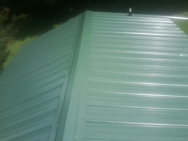 New green metal panels meeting at the ridge of a roof — Flat Roof Repair work by our crew in Ellijay