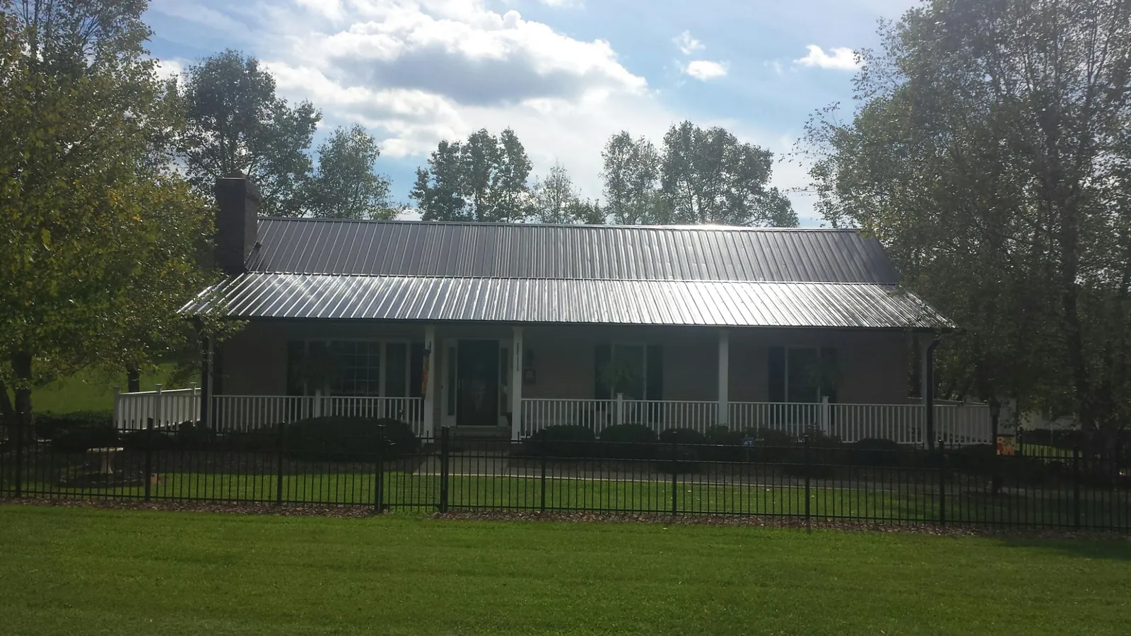 Gray metal roof on a brick ranch with a full width front porch — Gutter Guard Installation work by our crew in Ellijay
