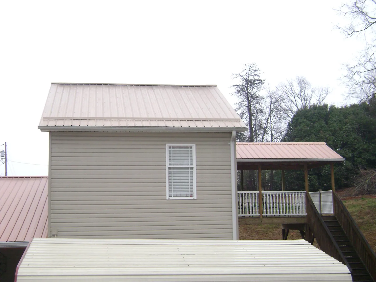 Tan metal roofs on a two story addition and attached porch, from a Roof Replacement job in Ellijay