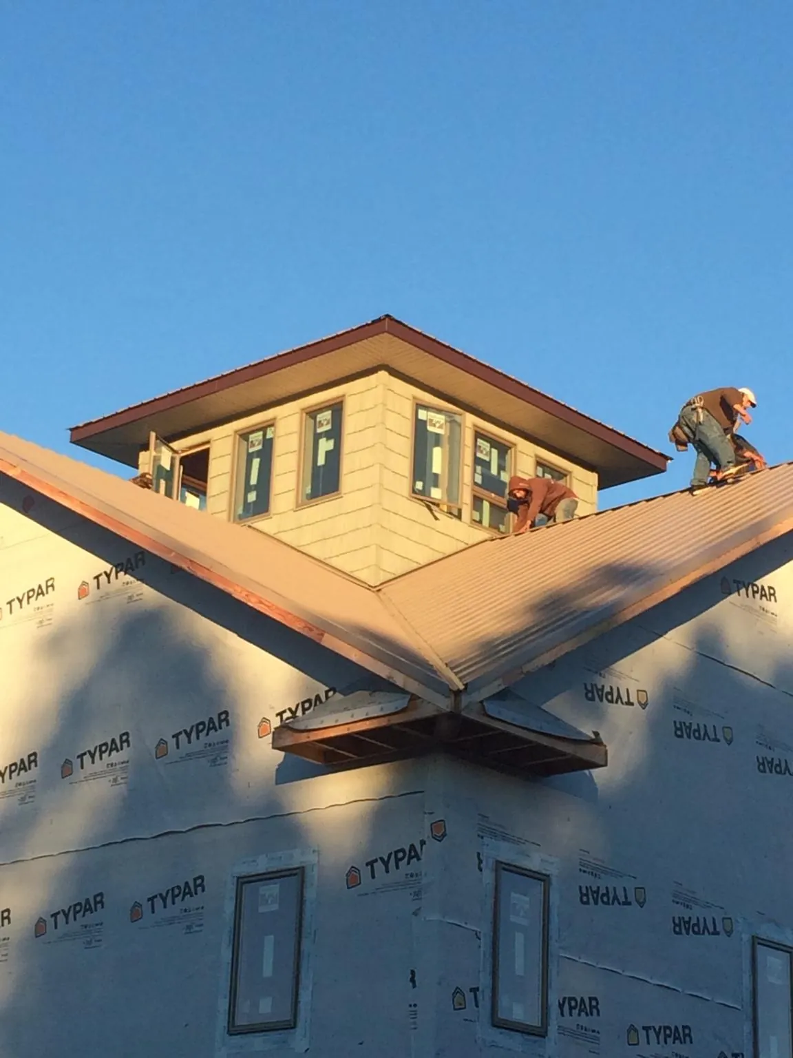 Roofers working around a rooftop cupola on a new metal roof at sunset — Roof Waterproofing in Ellijay by Roofing Brothers